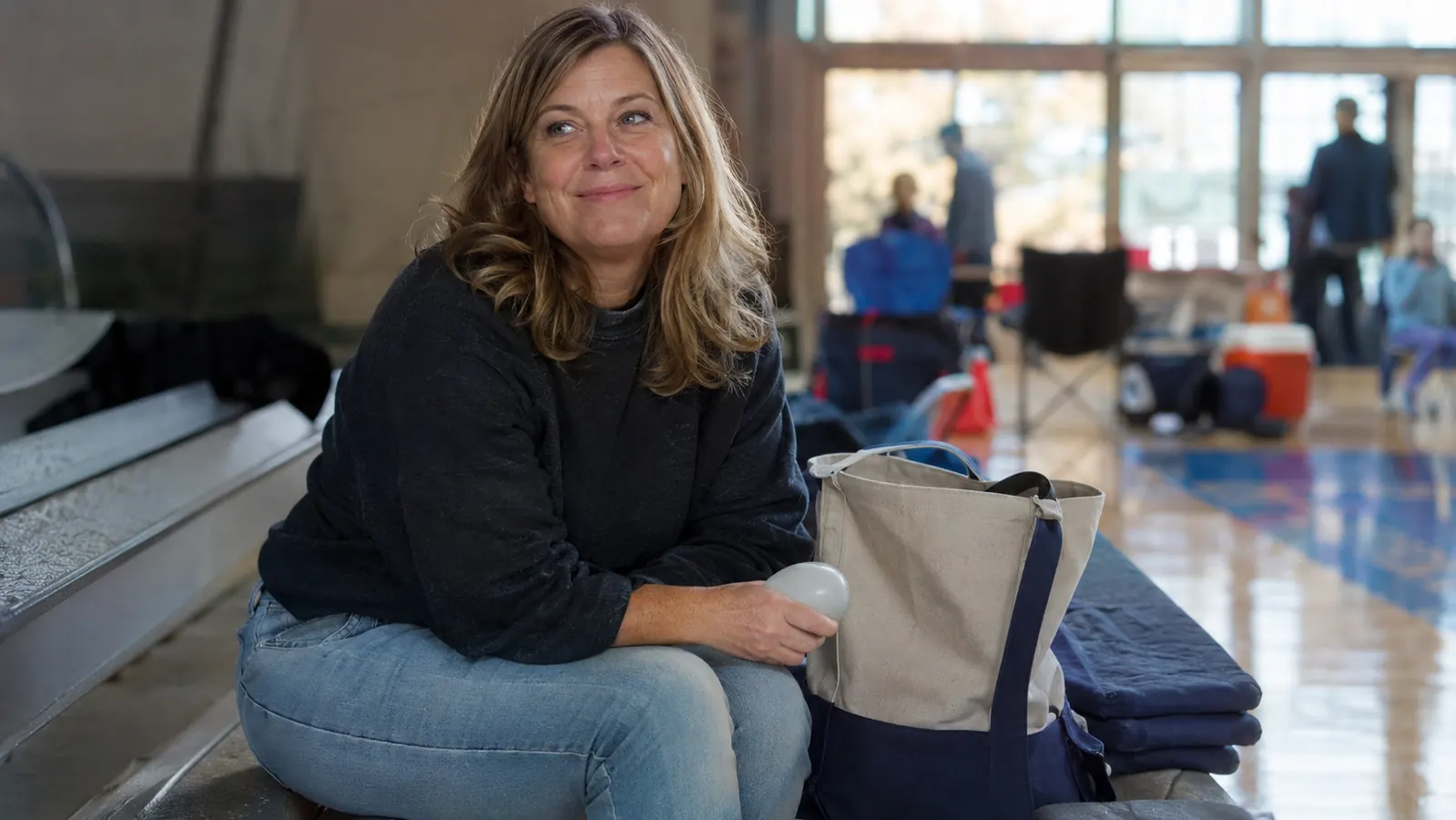 A small ice roller sitting on top of a folded stack of gym bleacher cushions next to a tournament bag and water bottles